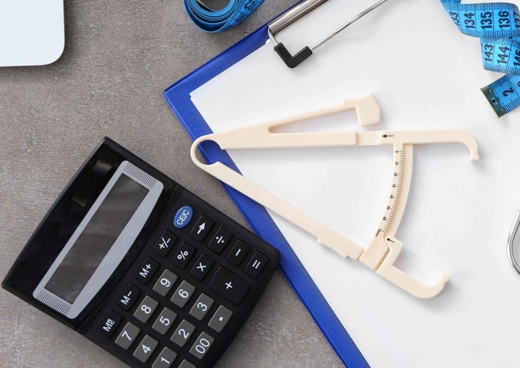 Natural Alternatives to Ozempic for Weight Loss 10 A calculator, scissors, glasses, and a tape measure arranged on a flat surface, representing tools for measurement and calculation.