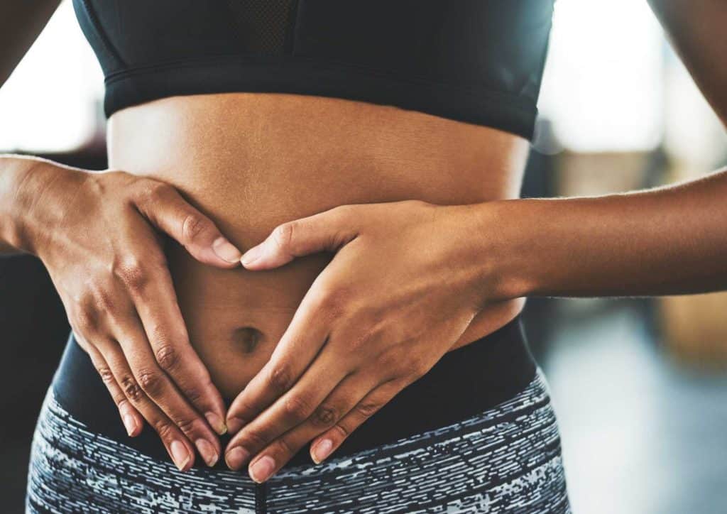 Natural Alternatives to Ozempic for Weight Loss 17 A woman stands with her hands on her stomach, appearing to express discomfort or concern.