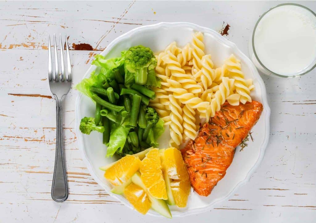 Not Losing Weight in a Calorie Deficit? Here's Why 16 A serving of pasta topped with salmon fillet and a variety of fresh vegetables on a white plate.