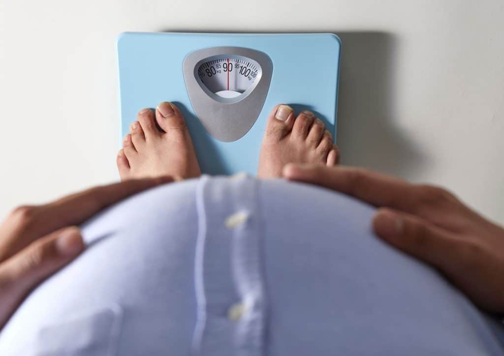 Not Losing Weight in a Calorie Deficit? Here's Why 12 Pregnant woman's feet positioned on a scale, indicating weight measurement during pregnancy.