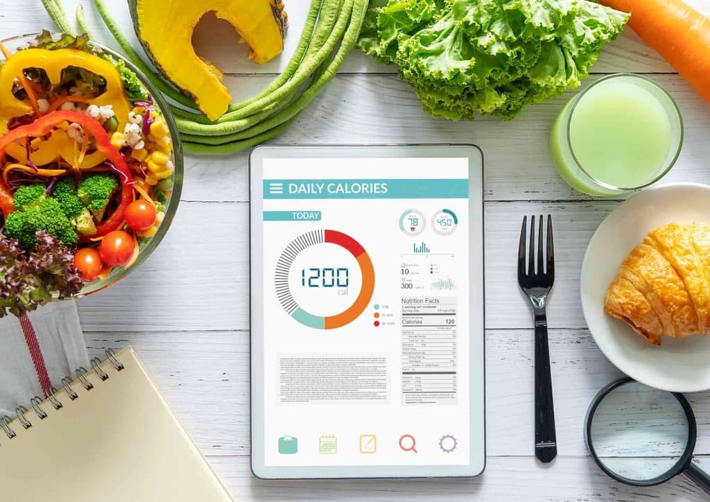 Not Losing Weight in a Calorie Deficit? Here's Why 1 A person writing in a food diary, tracking meals and snacks to aid in weight loss efforts.