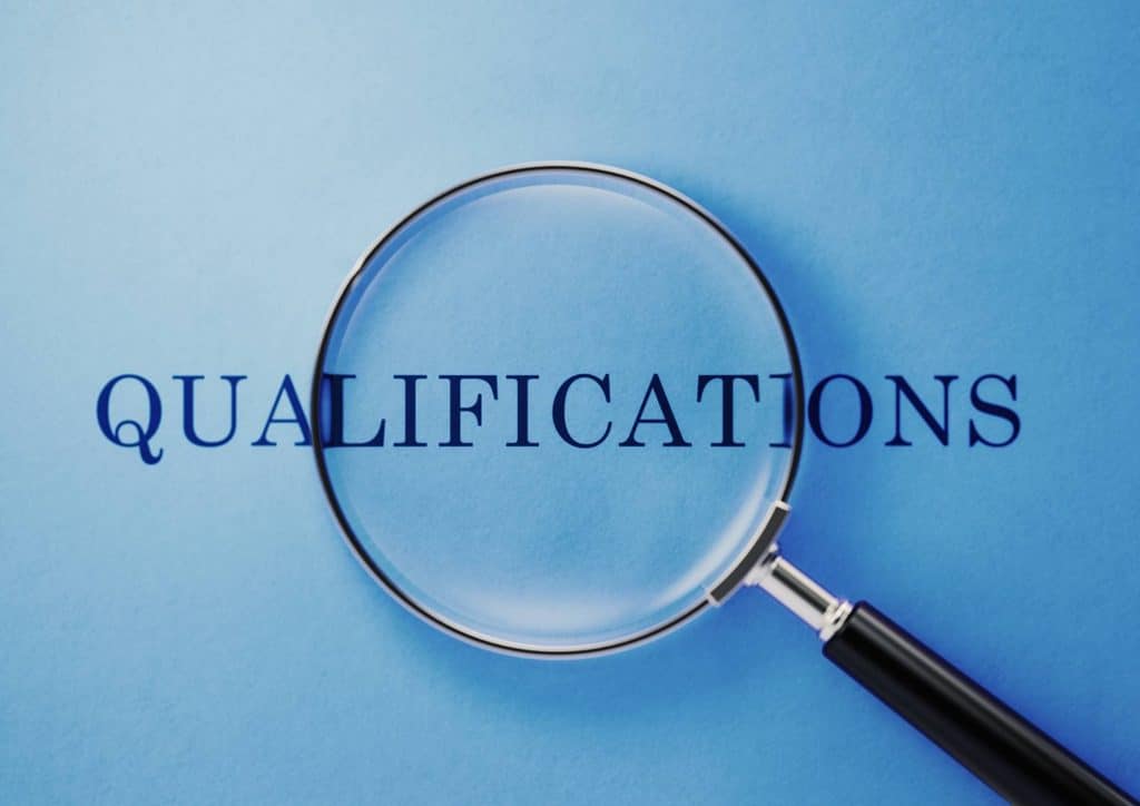 How to Choose the Best Weight Loss Nutritionist in Sydney 10 A magnifying glass focuses on the word "qualifications" against a blue background, symbolising scrutiny and assessment.