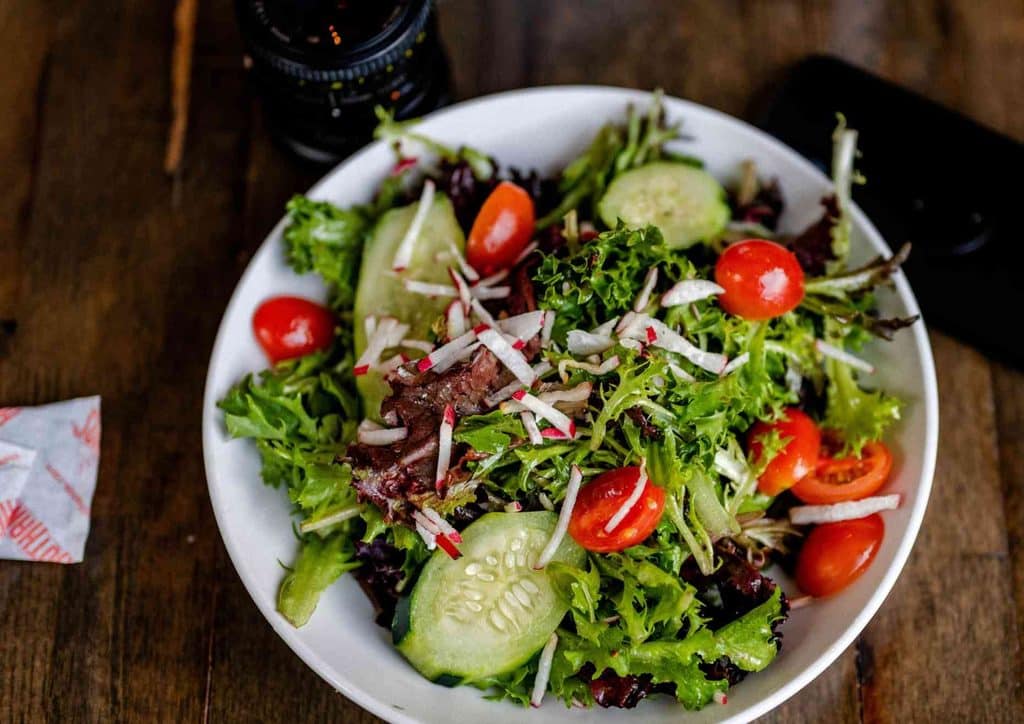 Natural Alternatives to Ozempic for Weight Loss 9 A fresh salad featuring sliced tomatoes, cucumbers, and crumbled cheese on a white plate.