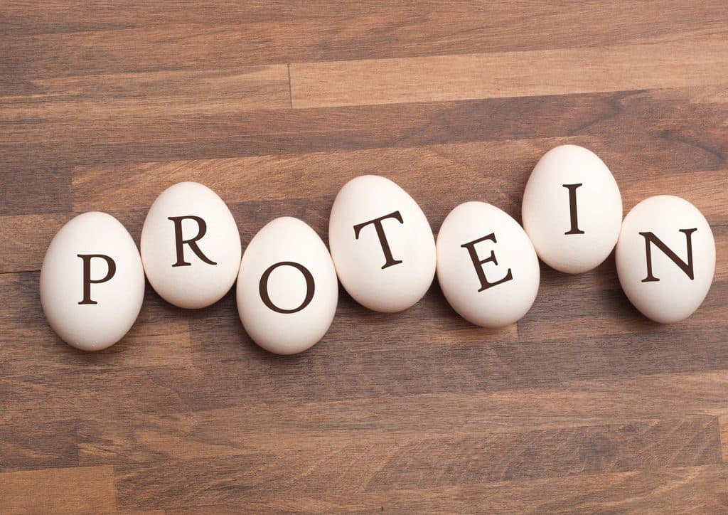How to Lose Weight Fast (Safely, Without Crashing) 9 The word "protein" formed with eggs on a rustic wooden table surface.