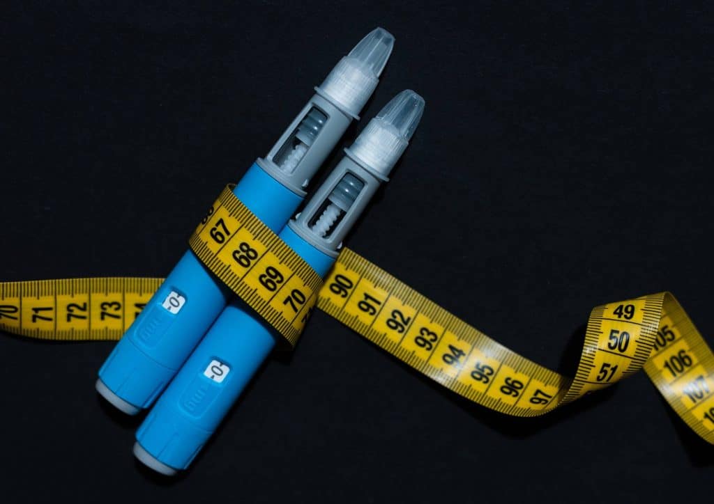Natural Alternatives to Ozempic for Weight Loss 1 Two blue pens wrapped in clear tape, positioned side by side on a white background.