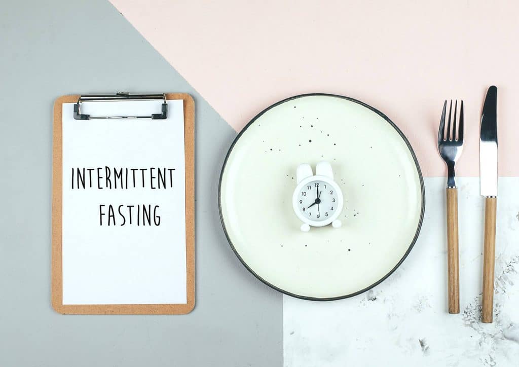 Intermittent Fasting for Weight Loss: Does It Actually Work? 1 Clipboard displaying "intermittent fasting" beside a fork, knife, and spoon on a wooden surface.