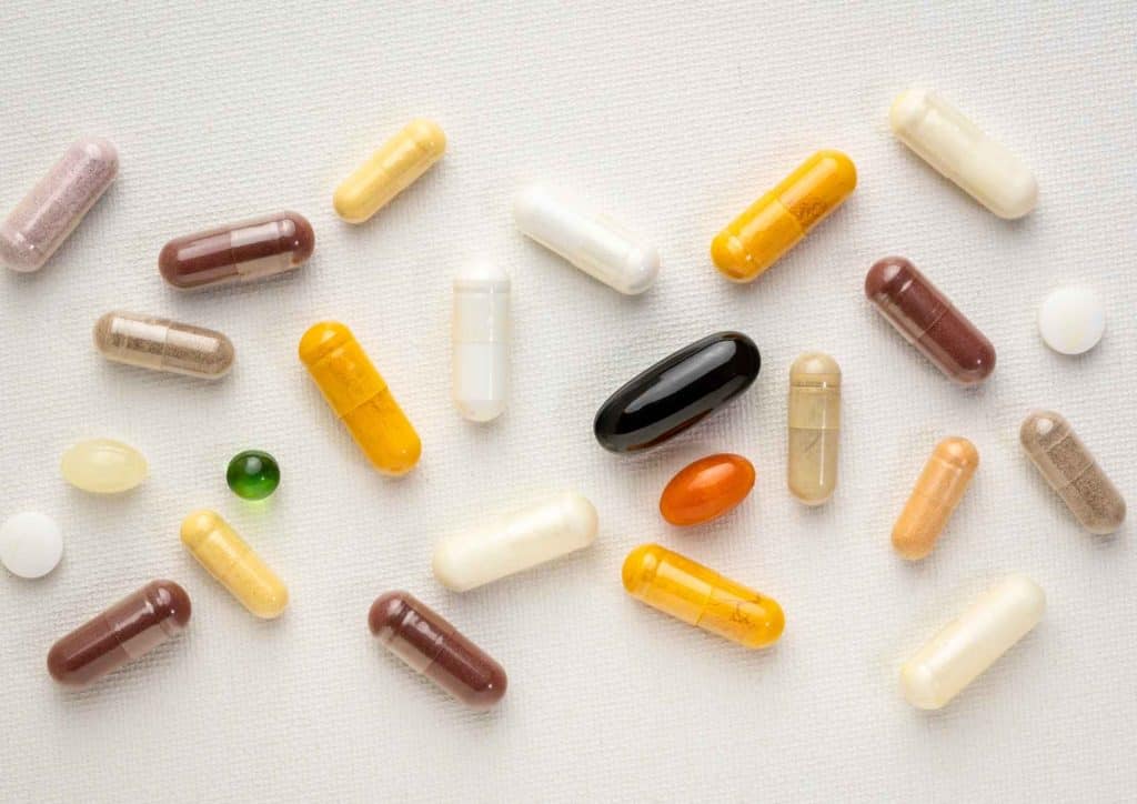 How to Speed Up Your Metabolism (What Actually Works) 19 A variety of pills and capsules in different shapes and colours scattered across a white surface.