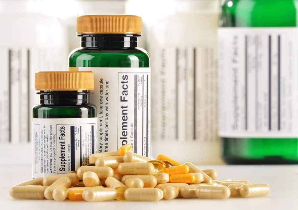 How to Speed Up Your Metabolism (What Actually Works) 29 A bottle of vitamin pills and capsules displayed on a wooden surface, showcasing various colors and shapes of the supplements.