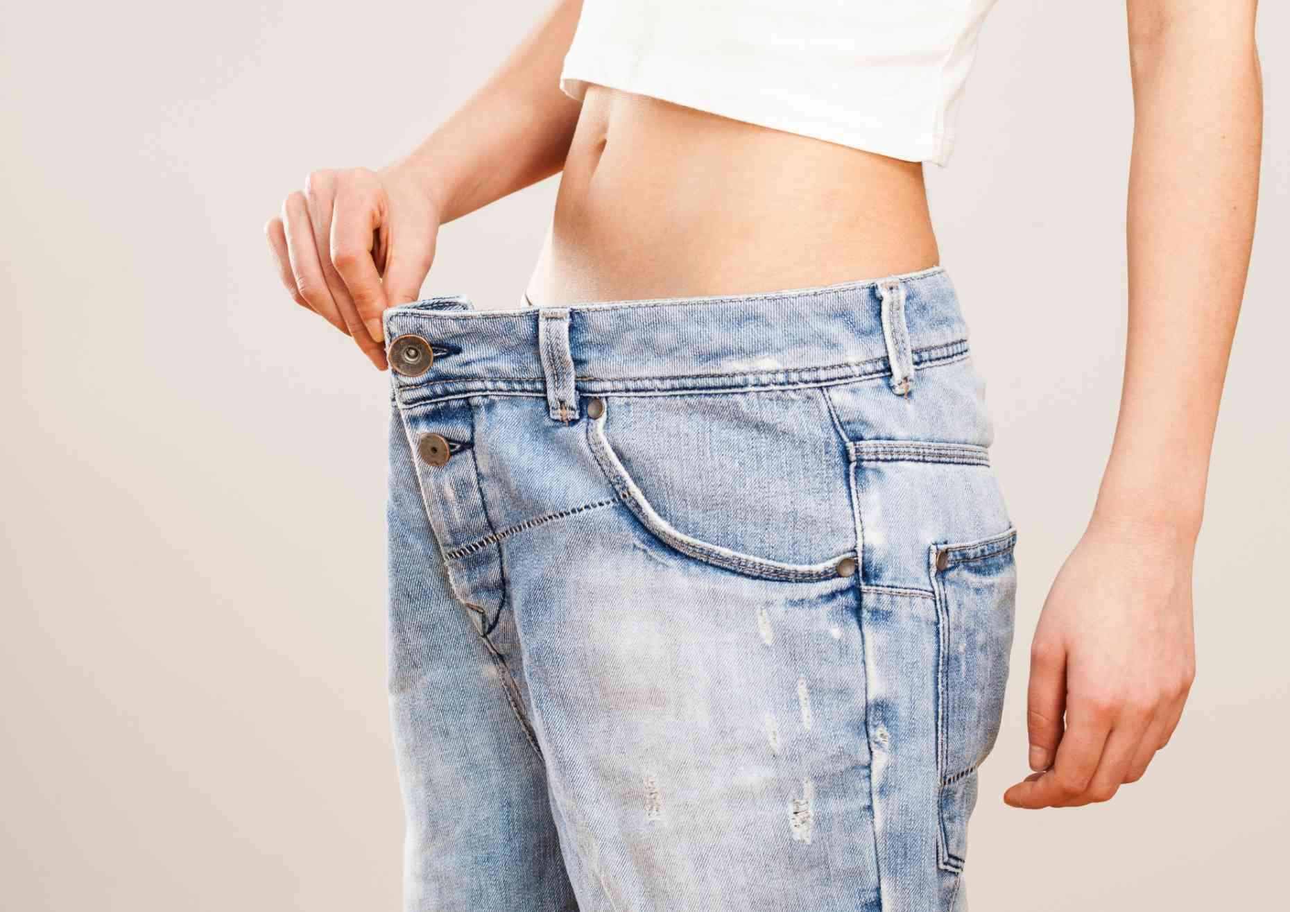 How to Choose the Best Weight Loss Nutritionist in Sydney 1 A woman measures her waist with a tape measure, focusing on her midsection for fitness or health tracking.