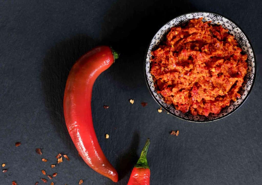 How to Speed Up Your Metabolism (What Actually Works) 24 A bowl of chili powder surrounded by two whole red peppers on a wooden surface.