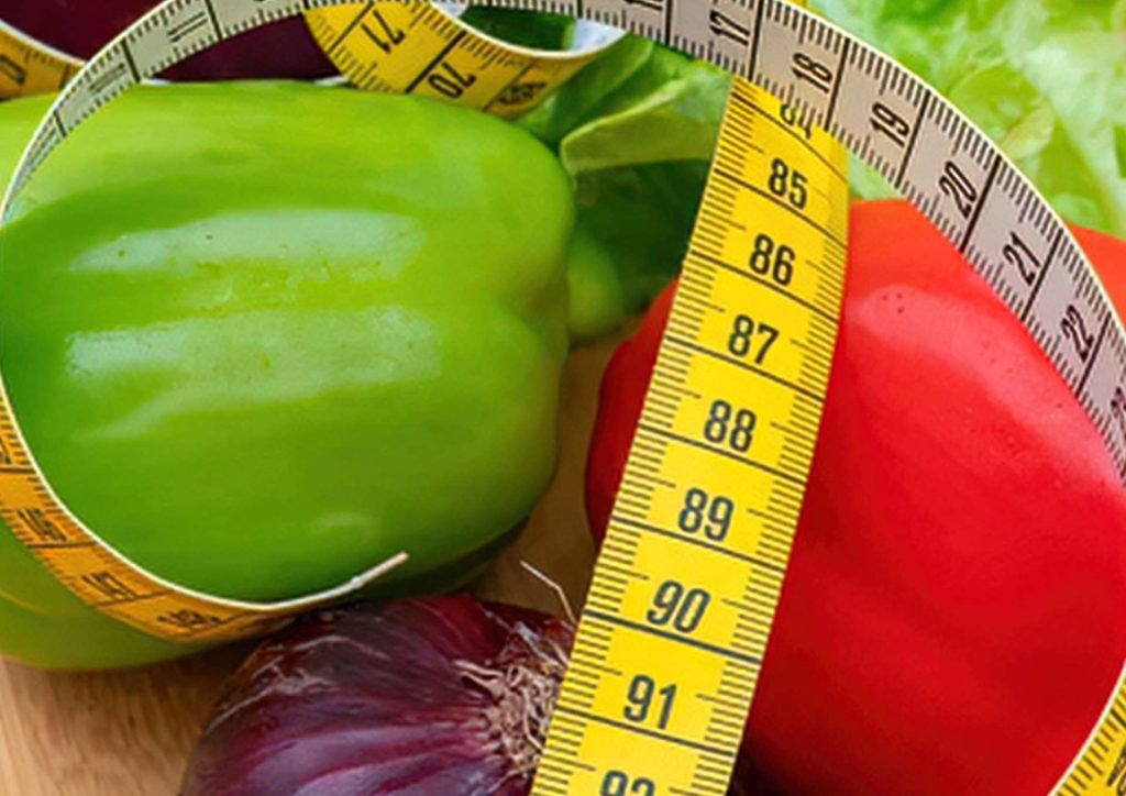 How to Lose Weight Without Exercise 6 A measuring tape encircles a variety of fresh vegetables, illustrating portion sizes and healthy eating.