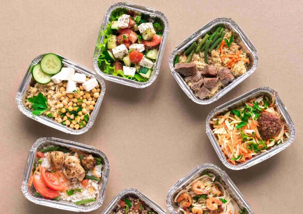How to Speed Up Your Metabolism (What Actually Works) 23 A circular arrangement of six food containers, each filled with different colourful dishes, displayed on a white surface.