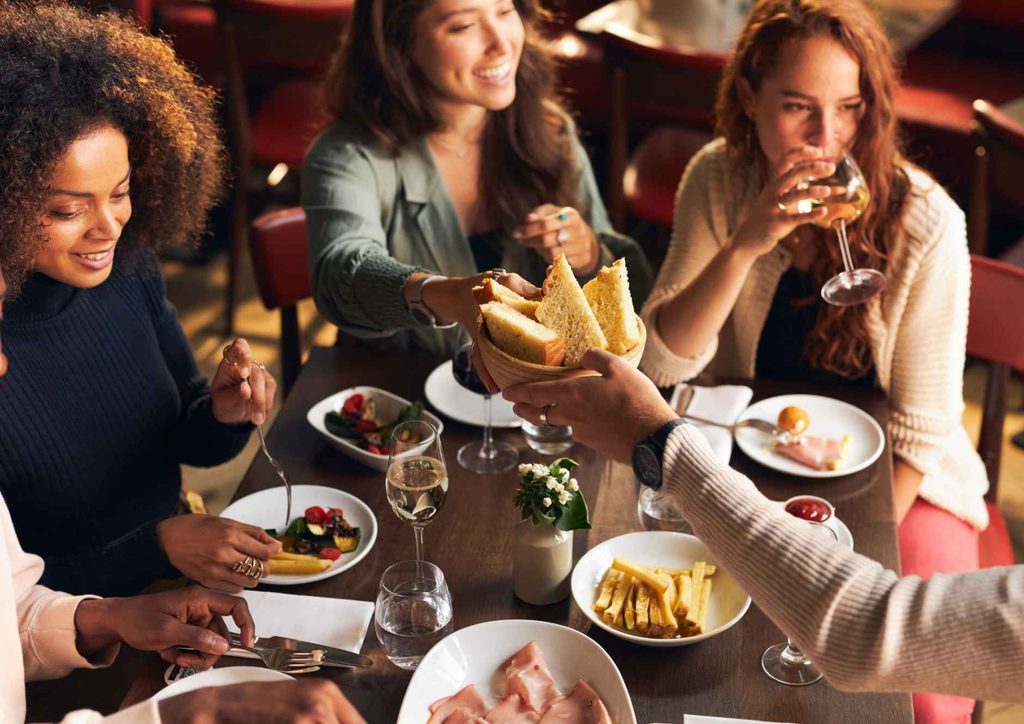 Why Am I Not Losing Weight? 8 Reasons a Nutritionist Sees Every Week 6 A group of diverse individuals seated at a table, enjoying a meal with various dishes and drinks.