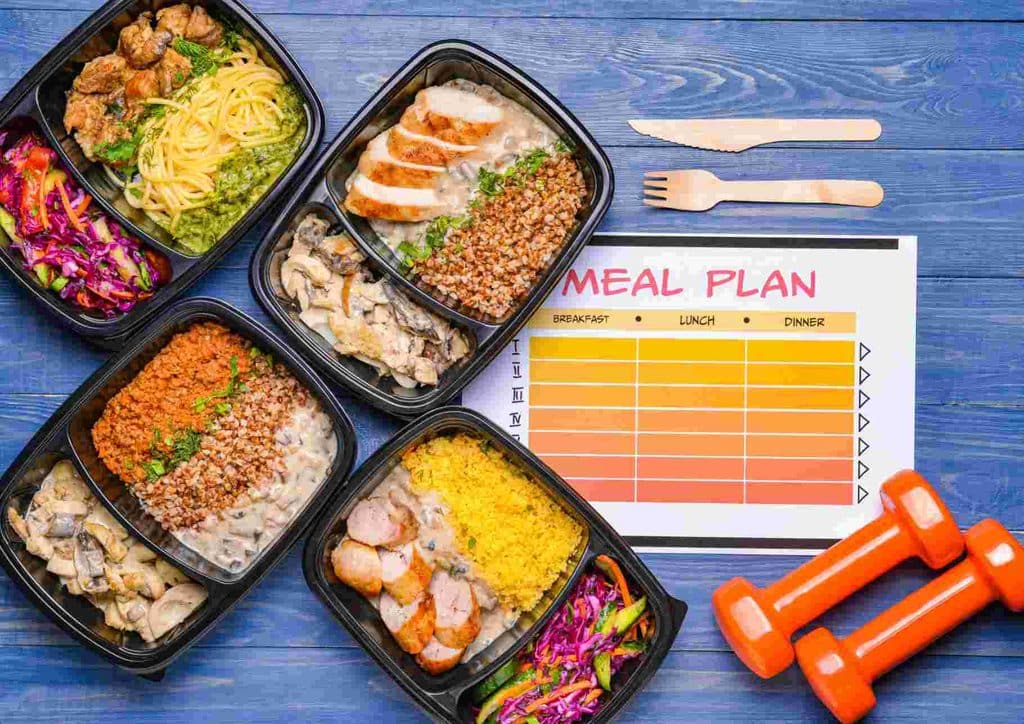 Why Am I Not Losing Weight? 8 Reasons a Nutritionist Sees Every Week 27 A meal plan displayed alongside various exercise equipment, illustrating a balanced approach to nutrition and fitness.