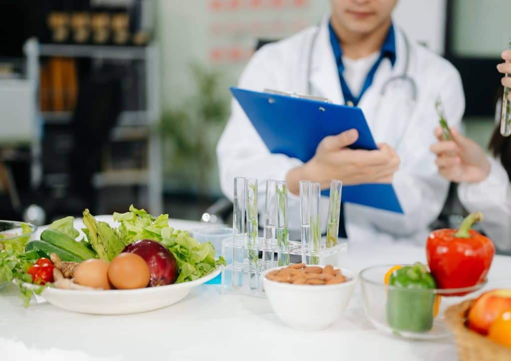 Why Am I Not Losing Weight? 8 Reasons a Nutritionist Sees Every Week 26 Two doctors examine a clipboard while holding glasses of water, engaged in a discussion in a clinical setting.