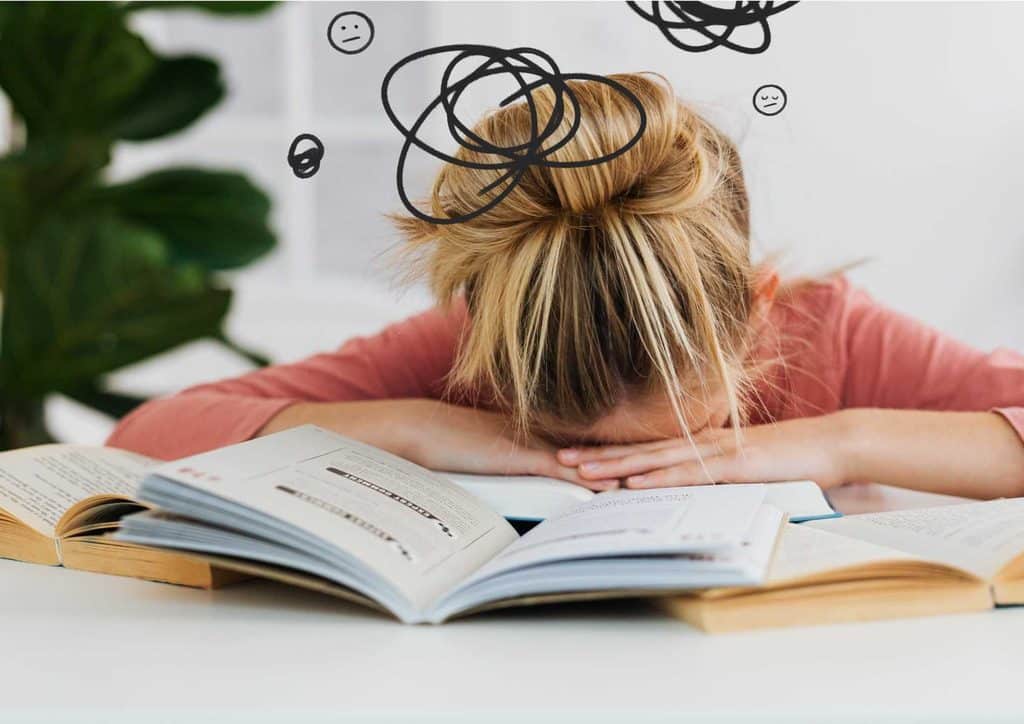 Why Am I Not Losing Weight? 8 Reasons a Nutritionist Sees Every Week 16 A girl sleeps on a table, with an open book and a doodle beside her, creating a serene and studious atmosphere.