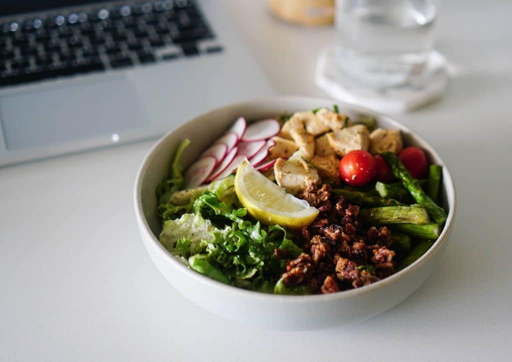 Vegetarian Diet for Weight Loss: How to Get It Right 9 A vibrant salad bowl containing assorted vegetables, meat pieces, and garnished with lemon wedges.