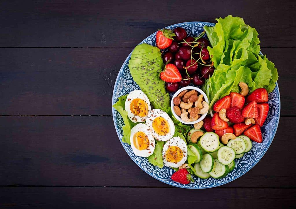 What Is a Balanced Diet for Weight Loss? 5 A plate filled with a variety of fresh produce, including strawberries, cucumbers, and oranges, arranged attractively.