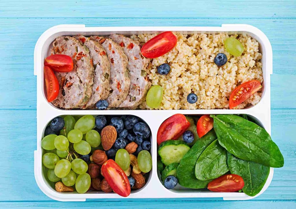 What Is a Balanced Diet for Weight Loss? 2 A lunch box filled with rice, fresh fruits, and vibrant vegetables, showcasing a balanced meal.