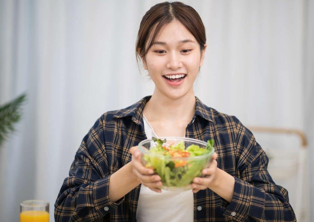 Easy Meals for Weight Loss When You're Short on Time 53 A woman holds a colourful salad in her hands, showcasing fresh vegetables and greens.