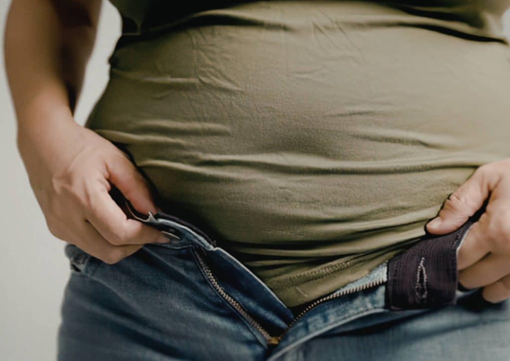 Postpartum Weight Loss: A Gentle, Realistic Guide 1 A woman in jeans gently holds her belly, conveying a sense of comfort or contemplation.