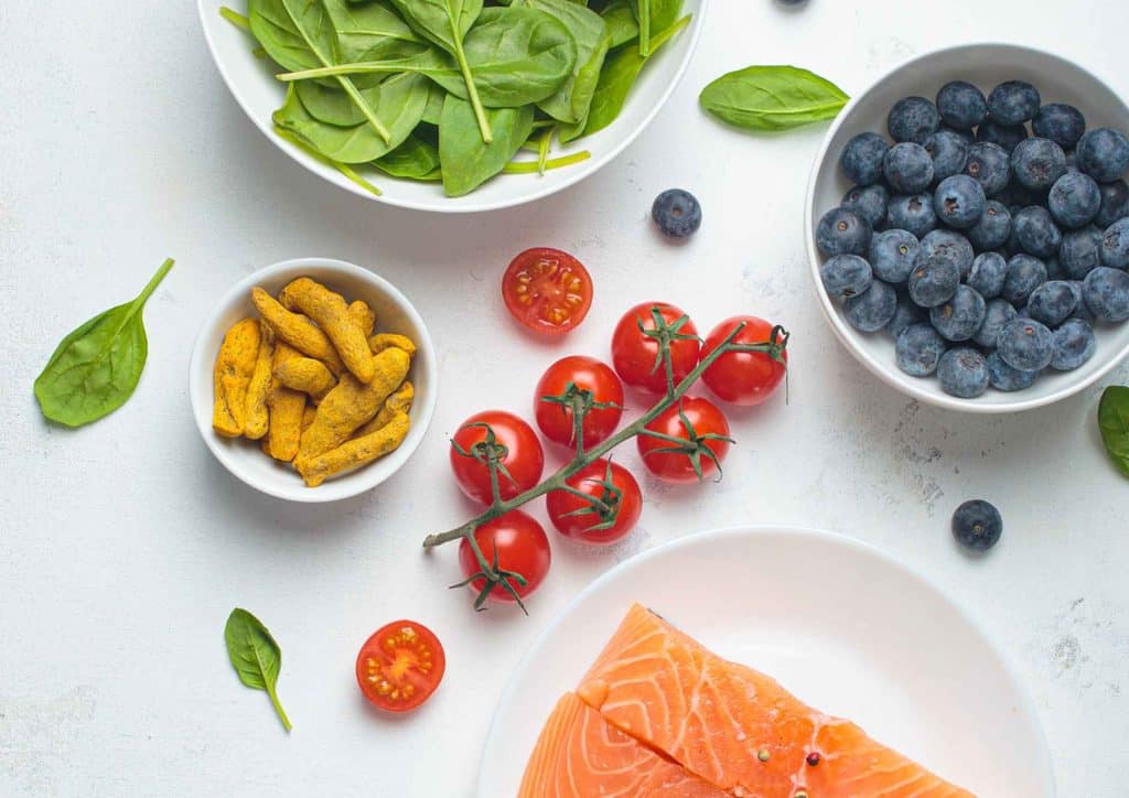 What Is a Balanced Diet for Weight Loss? 14 A white table displays an arrangement of salmon, blueberries, spinach, and various other foods.