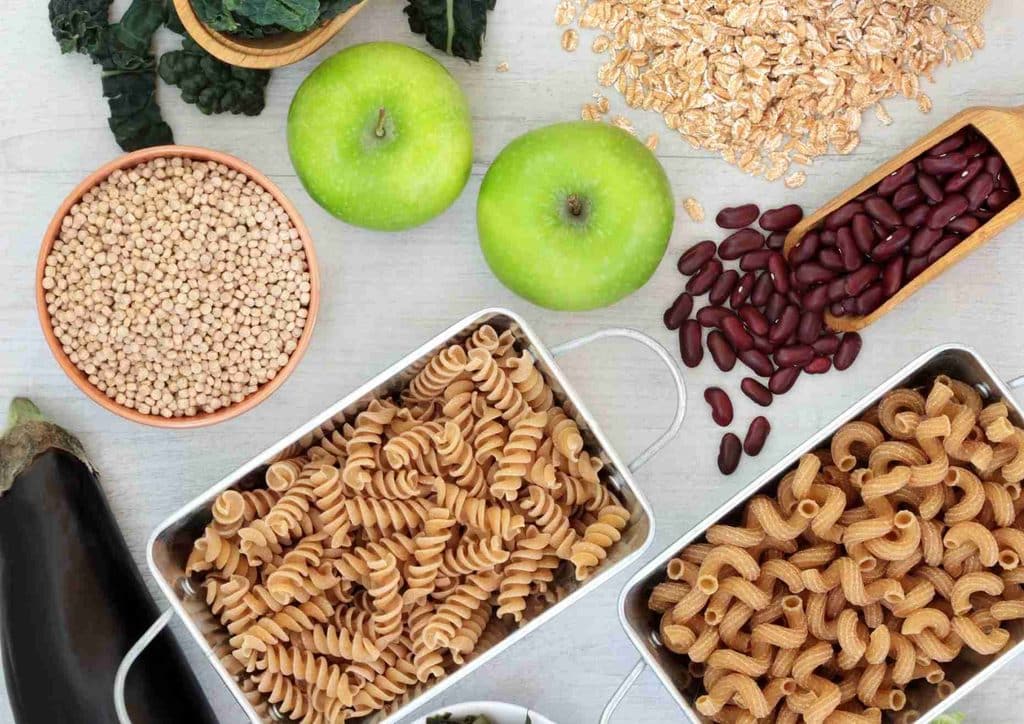 High Fibre Diet for Weight Loss: Why Fibre Keeps You Full 50 A diverse spread of pasta, beans, and assorted vegetables displayed on a rustic wooden surface.