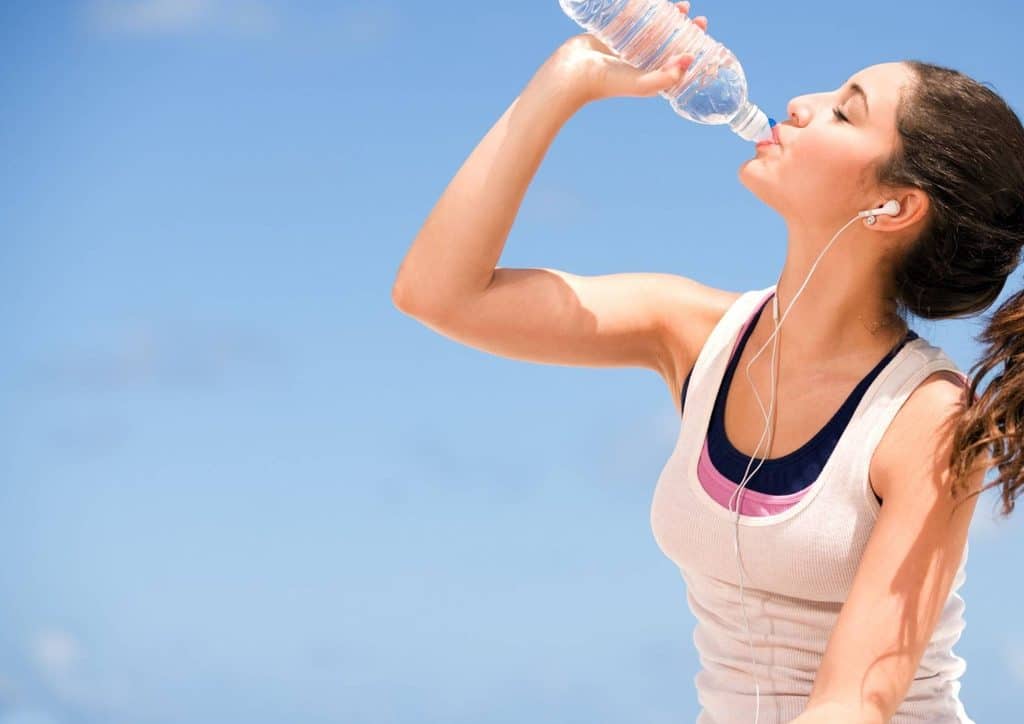 High Fibre Diet for Weight Loss: Why Fibre Keeps You Full 49 A woman takes a refreshing sip from a clear water bottle, enjoying hydration outdoors.