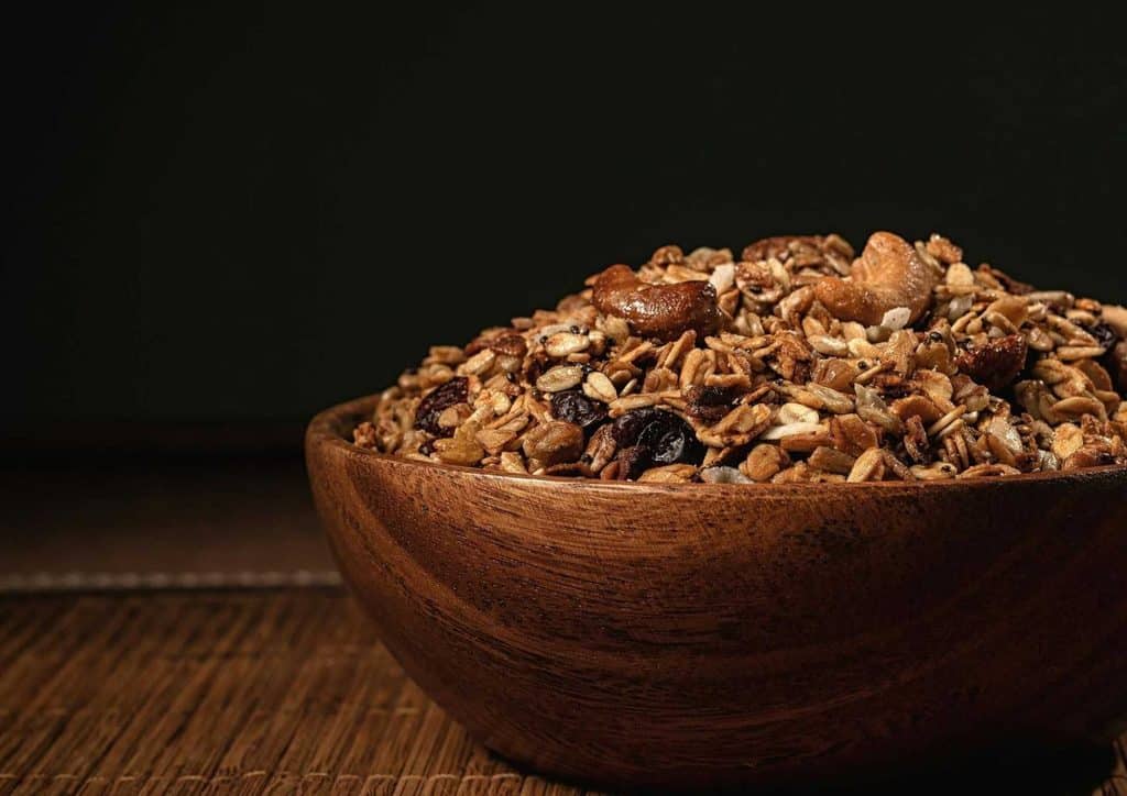 High Fibre Diet for Weight Loss: Why Fibre Keeps You Full 52 A wooden bowl filled with granola, showcasing a mix of oats, nuts, and dried fruits.
