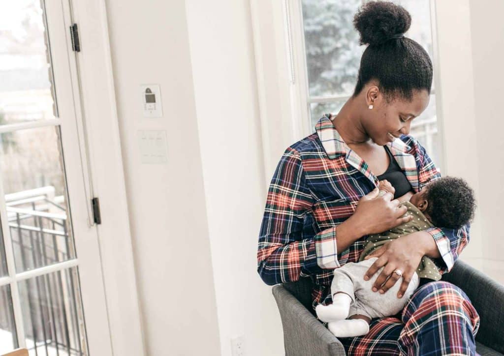 Losing Weight While Breastfeeding: What's Safe and Realistic 3 A woman in pajamas gently holds her baby, showcasing a tender moment of care and affection.