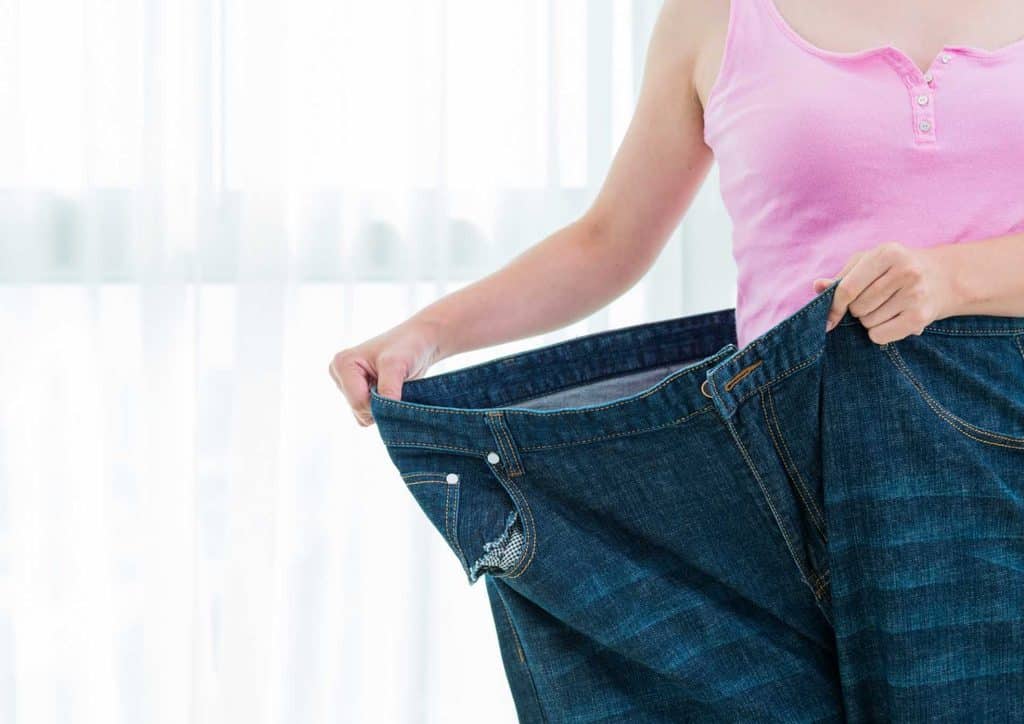 Losing Weight While Breastfeeding: What's Safe and Realistic 11 A woman holds up a pair of jeans, showcasing their fit and style.