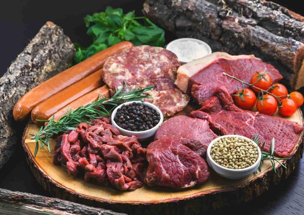Is Whey Protein Good for Weight Loss? 41 A wooden board displaying an assortment of raw meat and fresh vegetables arranged for meal preparation.