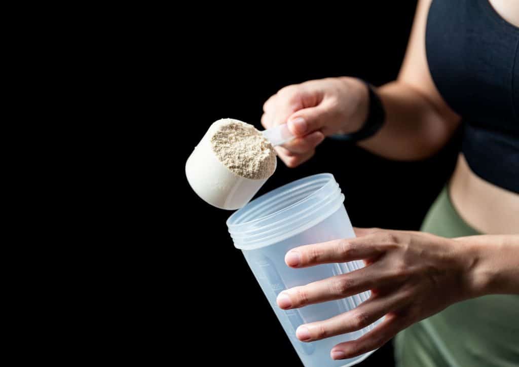 Is Whey Protein Good for Weight Loss? 50 A woman holds a shaker filled with powder, preparing to mix a drink or supplement.