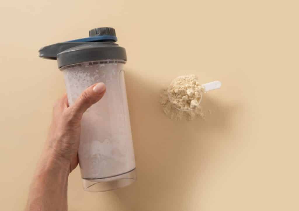 Is Whey Protein Good for Weight Loss? 49 A person holding a blender filled with a scoop of protein powder, preparing to make a protein shake.