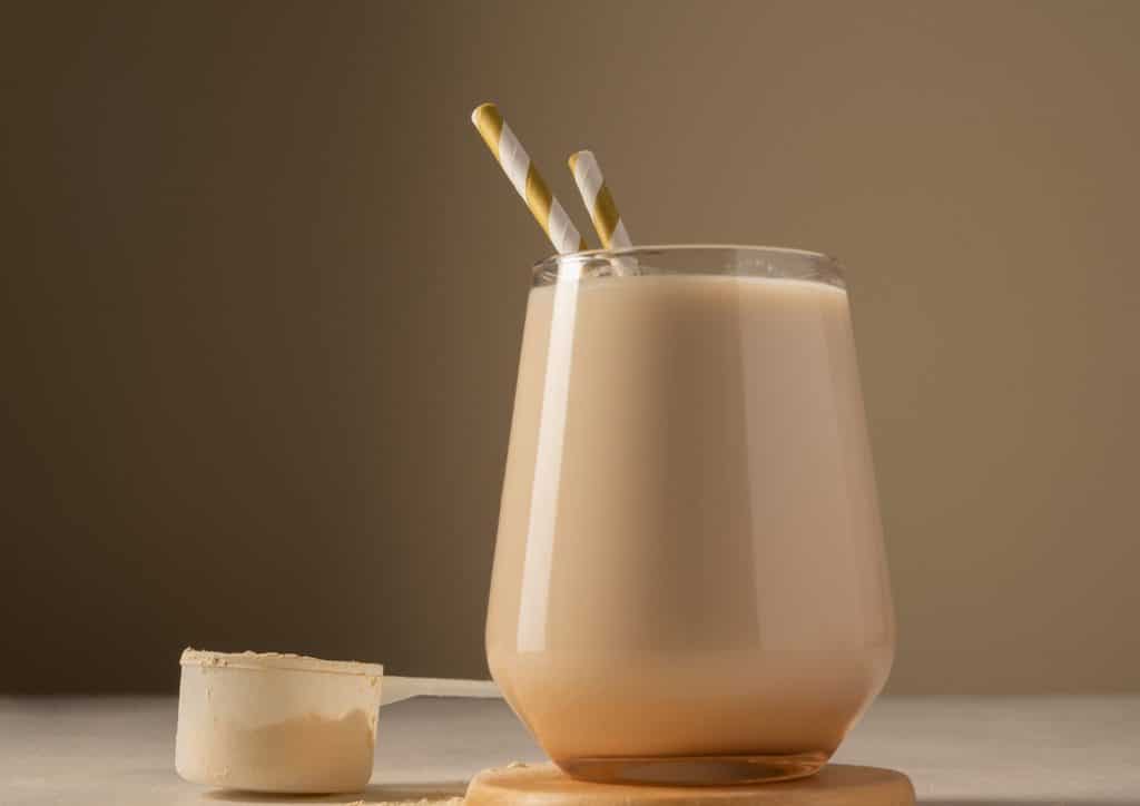 Is Whey Protein Good for Weight Loss? 48 A glass of milk with a straw beside a scoop of ice cream on a white background.