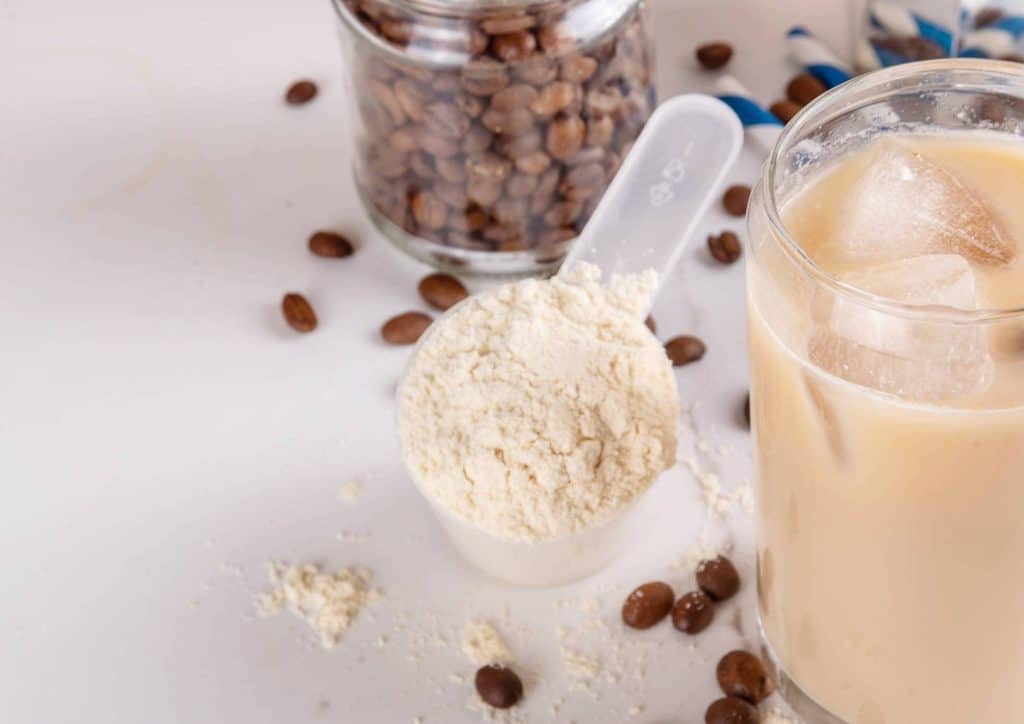 Is Whey Protein Good for Weight Loss? 46 A composition of coffee beans, a glass of milk, and a scoop of protein powder on a wooden surface.