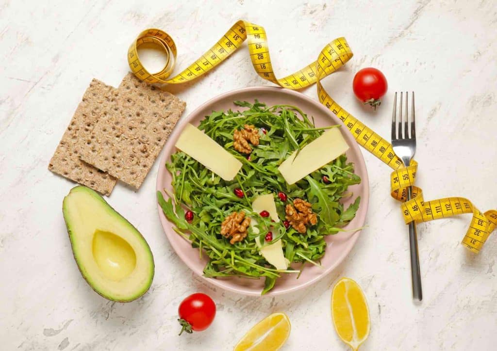 Easy Meals for Weight Loss When You're Short on Time 4 A plate of salad featuring avocado, cheese, and a measuring tape, symbolising healthy eating and portion control.