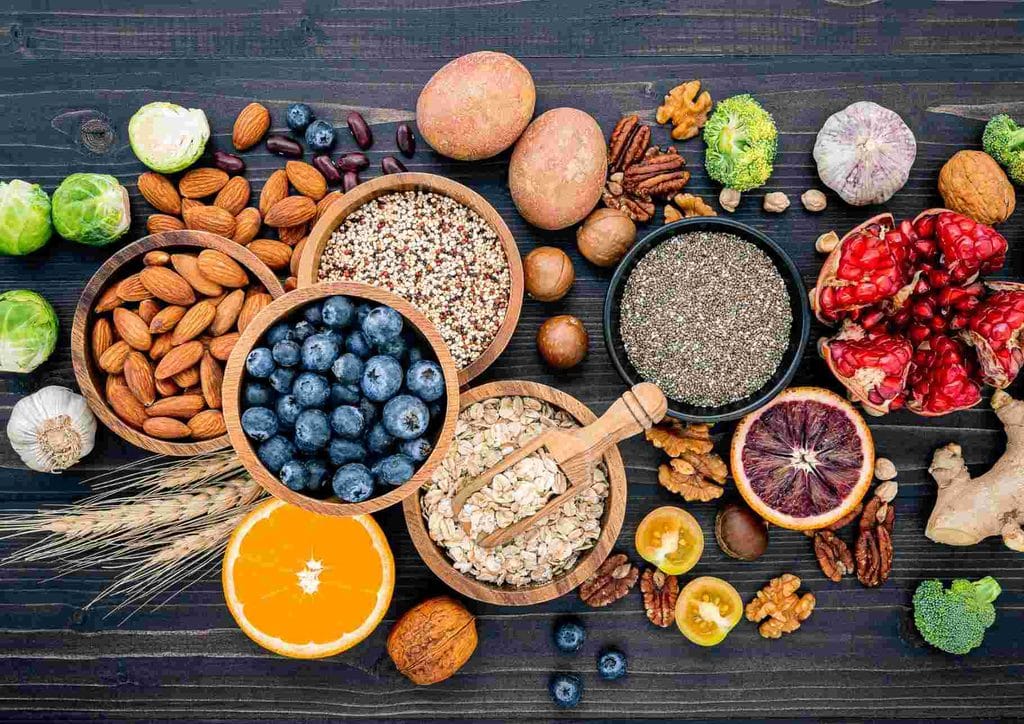 What Is a Balanced Diet for Weight Loss? 18 A variety of heart-healthy foods including fruits, vegetables, nuts, and whole grains displayed on a wooden table.
