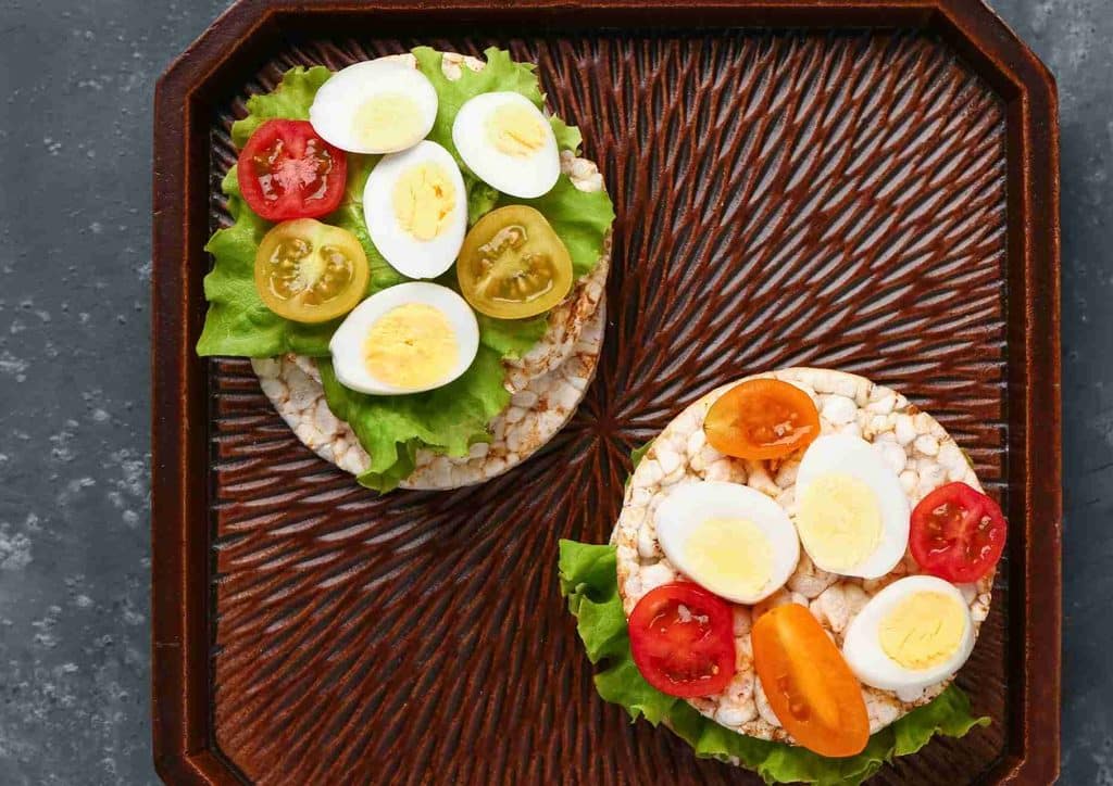 Easy Meals for Weight Loss When You're Short on Time 52 Two sandwiches with eggs, tomatoes, and lettuce arranged on a wooden tray.
