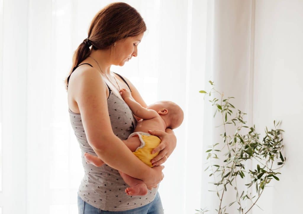 Postpartum Weight Loss: A Gentle, Realistic Guide 5 A woman gently cradles a baby in her arms, showcasing a tender moment of care and affection.