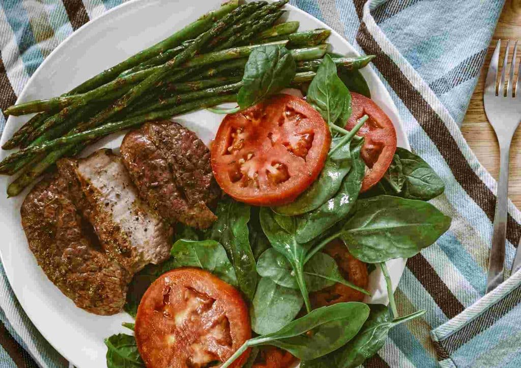 Healthy Dinners for Weight Loss: Easy Weeknight Ideas 8 A plate featuring grilled meat, fresh asparagus, and ripe tomatoes arranged artfully.