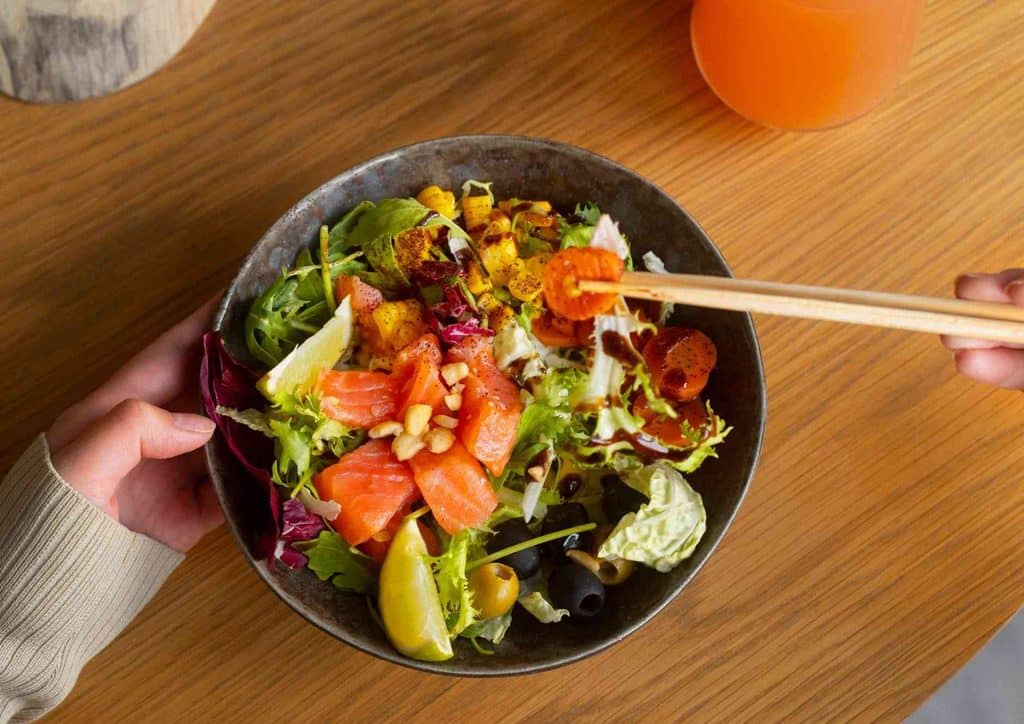 Healthy Dinners for Weight Loss: Easy Weeknight Ideas 9 A person using chopsticks to pick up salad from a bowl, showcasing a colourful mix of vegetables.