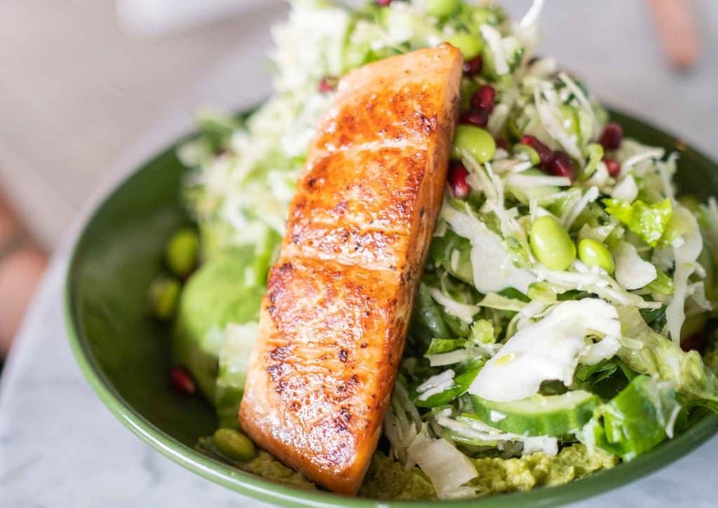 Healthy Dinners for Weight Loss: Easy Weeknight Ideas 26 A green bowl filled with salmon, fresh lettuce, and vibrant pomegranate seeds.