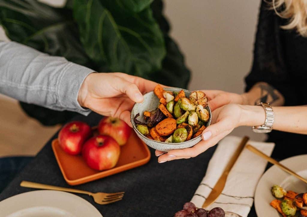 Healthy Dinners for Weight Loss: Easy Weeknight Ideas 29 A couple stands together, holding a bowl of food above a table, smiling at each other in a cozy setting.