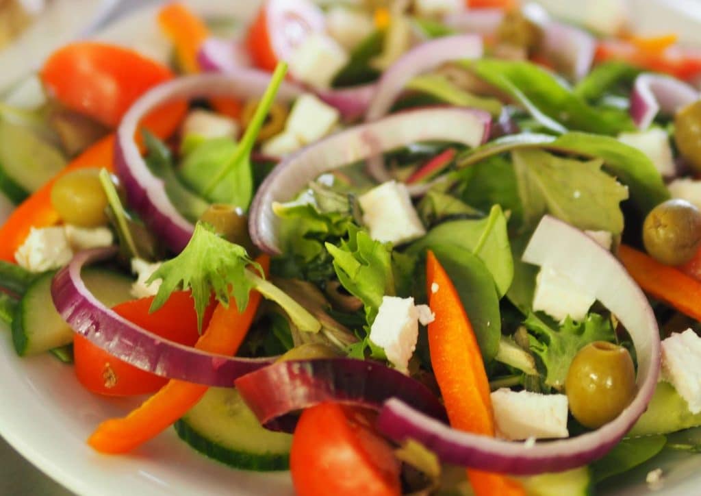 Healthy Lunches for Weight Loss: Work and Home Ideas 44 A fresh salad featuring cucumbers, tomatoes, onions, and crumbled feta cheese on a white plate.