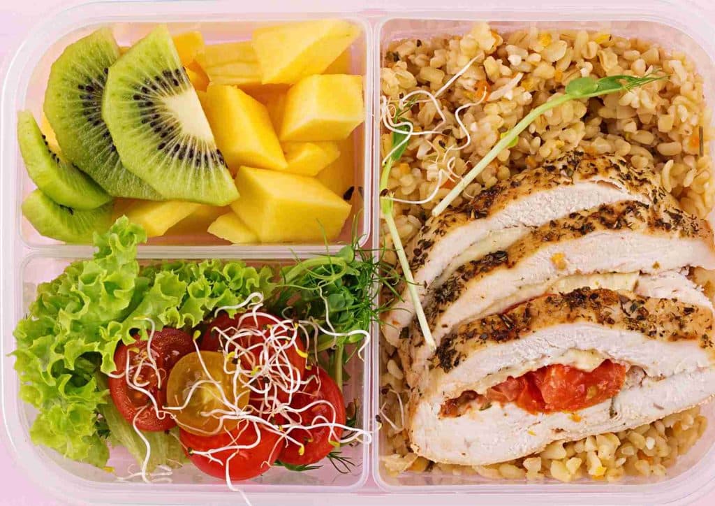 Healthy Lunches for Weight Loss: Work and Home Ideas 35 A plastic container holding a cooked chicken breast, white rice, and assorted fruit pieces.
