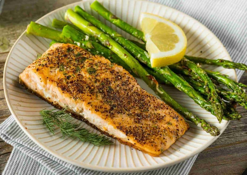 Healthy Lunches for Weight Loss: Work and Home Ideas 14 A plate featuring grilled salmon fillet alongside steamed asparagus spears, garnished with lemon slices.