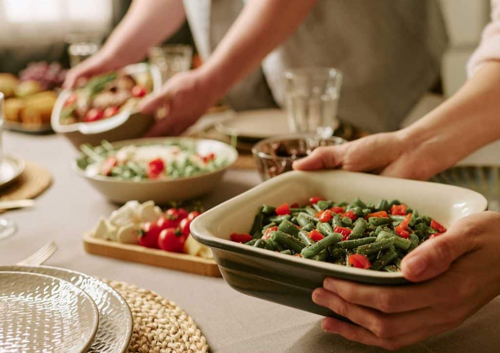 Healthy Lunches for Weight Loss: Work and Home Ideas 32 A group of individuals serving food at a beautifully set dinner table, showcasing a communal dining experience.
