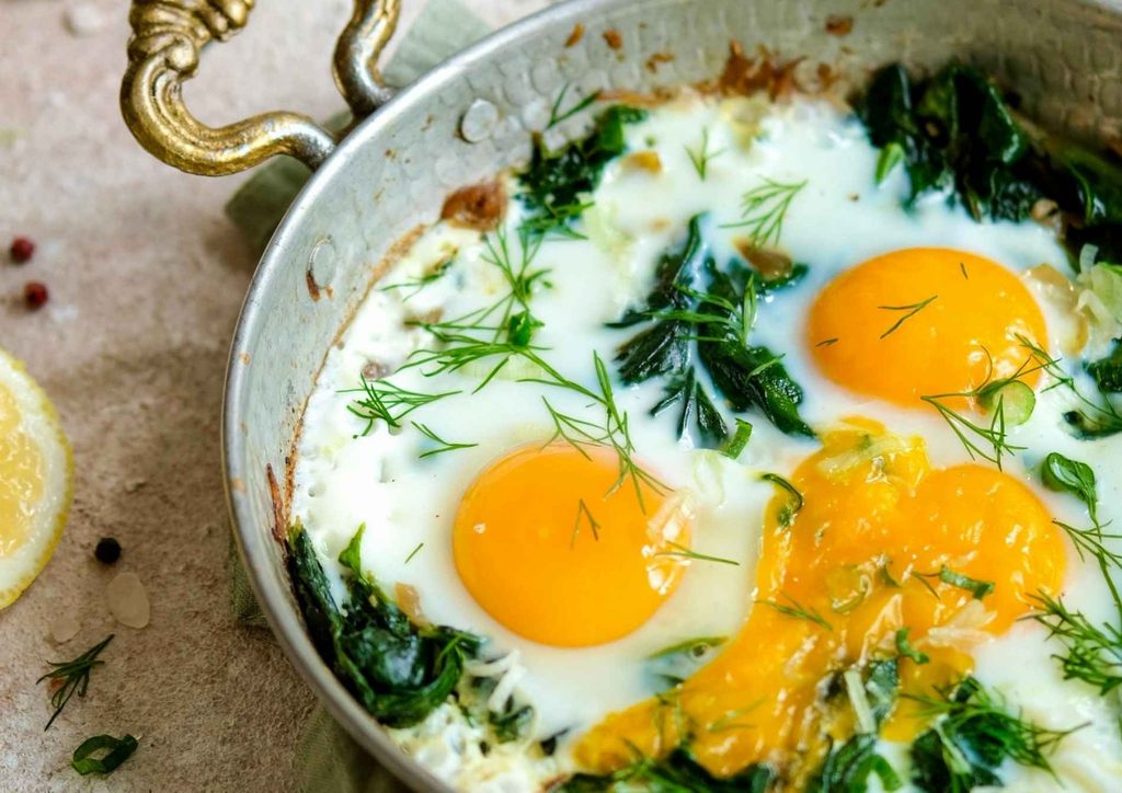 Healthy Lunches for Weight Loss: Work and Home Ideas 30 A close-up of a skillet with cooked spinach and eggs, topped with fresh lemon wedges for a vibrant presentation.