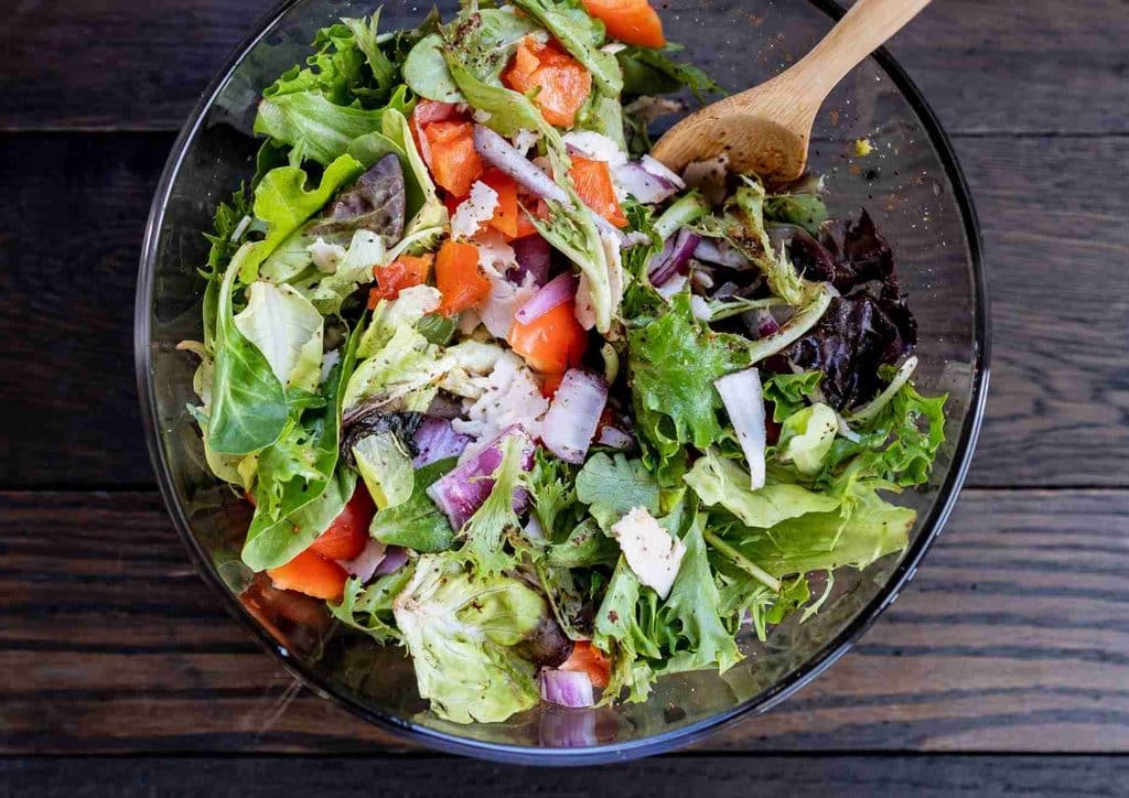 Healthy Dinners for Weight Loss: Easy Weeknight Ideas 33 A fresh salad featuring lettuce, tomatoes, onions, and crumbled feta cheese in a white bowl.